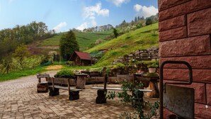 Un patio con bancos de piedra, un edificio rústico y campos escalonados al fondo.