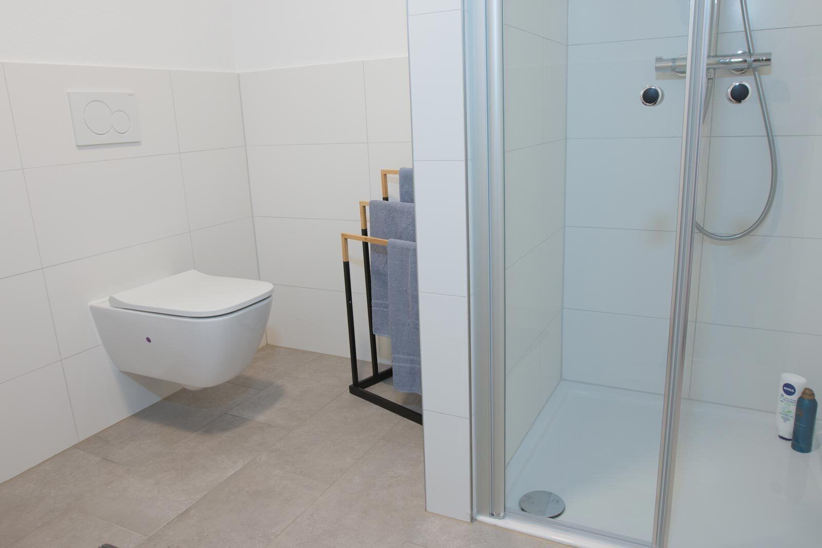 A modern bathroom with a toilet, a glass shower enclosure, and a towel rack.