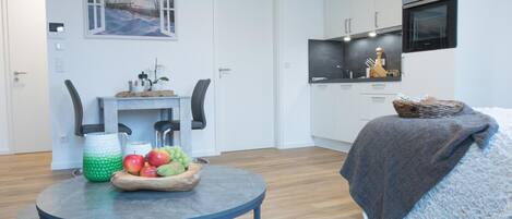 A modern apartment with a dining area, kitchenette, and a cozy seating area with a blanket.