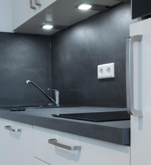 A modern kitchen with a black countertop, stainless steel faucet, and a built-in oven. - Boardinghouse Baumhof 55 (Marktheidenfeld)