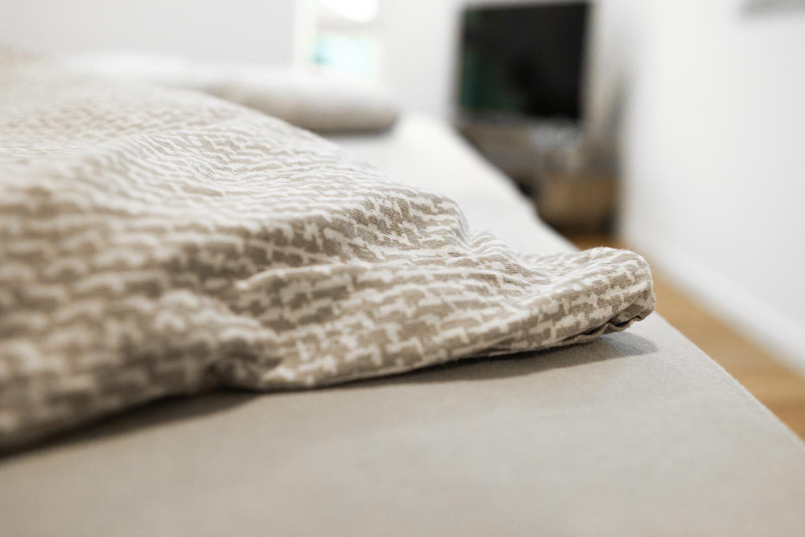 A close-up of a textured, patterned blanket on a bed.