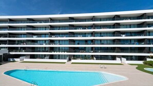 Et moderne hotel med flere etager, en swimmingpool og udendørs siddeområder.