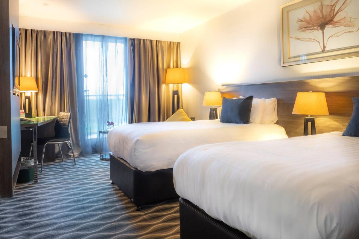 Habitació d'hotel amb dos llits, un escriptori i una cadira.