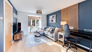 Un salon moderne comprenant un canapé, une table basse, un téléviseur et un bureau avec une chaise.