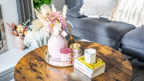 Ein runder Holztisch mit einer Blumenvase, einer Kerze und einem Buch.