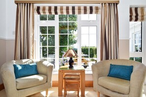 A room with two armchairs, a small table, and a window with curtains.