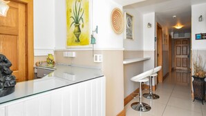 A modern kitchen with a white countertop, a yellow vase, and a painting of flowers. - Mannin Lodge by Connemara Shores (Ballyconneely)