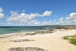 Una platja amb cel serè, mar tranquil·la i costa rocosa.