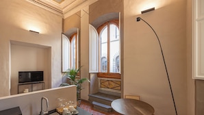 A modern kitchen with a sink, stove, and a dining area with a table and chair. - Maggio Living (Florence)