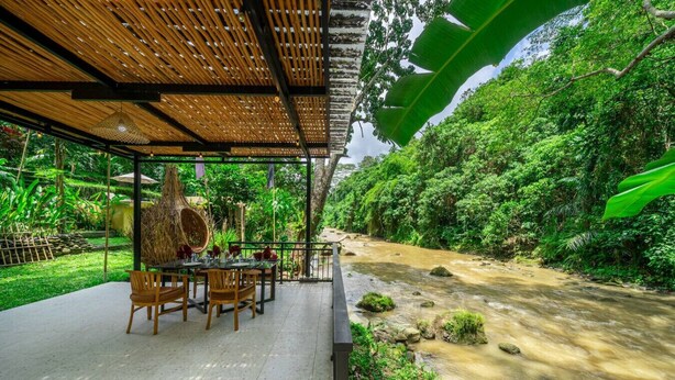 An outdoor dining area with a river view, bamboo ceiling, and lush greenery. - Jungle River Villa for 10 |Pool, ATV, Tubing| Ubud (Sukawati)