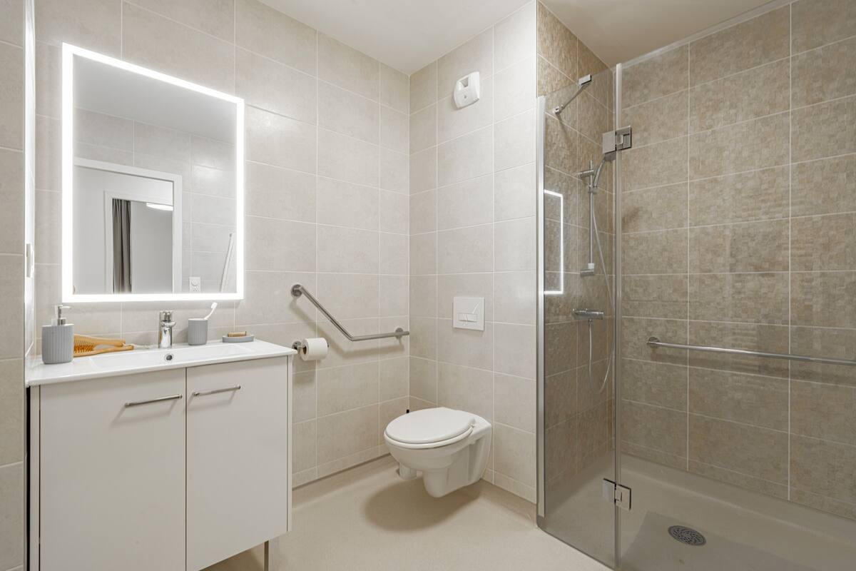 A modern bathroom with a toilet, sink, and shower.