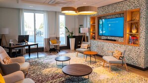 A modern hotel room with a large TV, comfortable seating, and a view of the outdoors. - Résidence de Bourges (Bourges)