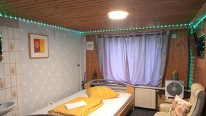 A bedroom with a bed, a chair, a radiator, and a wall-mounted TV. - Small Studio in Countryside *Simple and Affordable (Buchholz in der Nordheide)