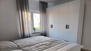 Une chambre à coucher avec un lit, une fenêtre avec des rideaux et une armoire.