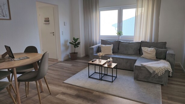 Un salon moderne comprenant un canapé, une table basse et un coin repas avec des chaises.