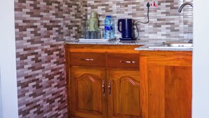 A kitchen with wooden cabinets, a tiled backsplash, and a sink. - Osim bnb (Arusha)