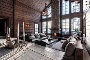Un intérieur chaleureux de chalet en bois avec une cheminée, de grandes fenêtres et un salon moderne.