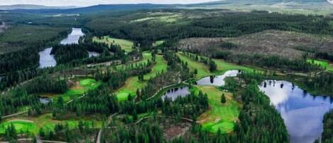 A panoramic view of a golf course with multiple ponds and dense forests.