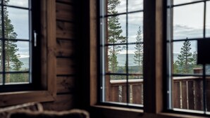 Ein Zimmer mit Fensterblick auf eine Holzterrasse und Bäume.