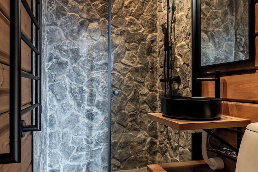A stone wall with a rustic wooden door and a black appliance on a wooden shelf.