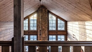 Un intérieur en bois avec un pilier en pierre, de grandes fenêtres et un plafond en bois.