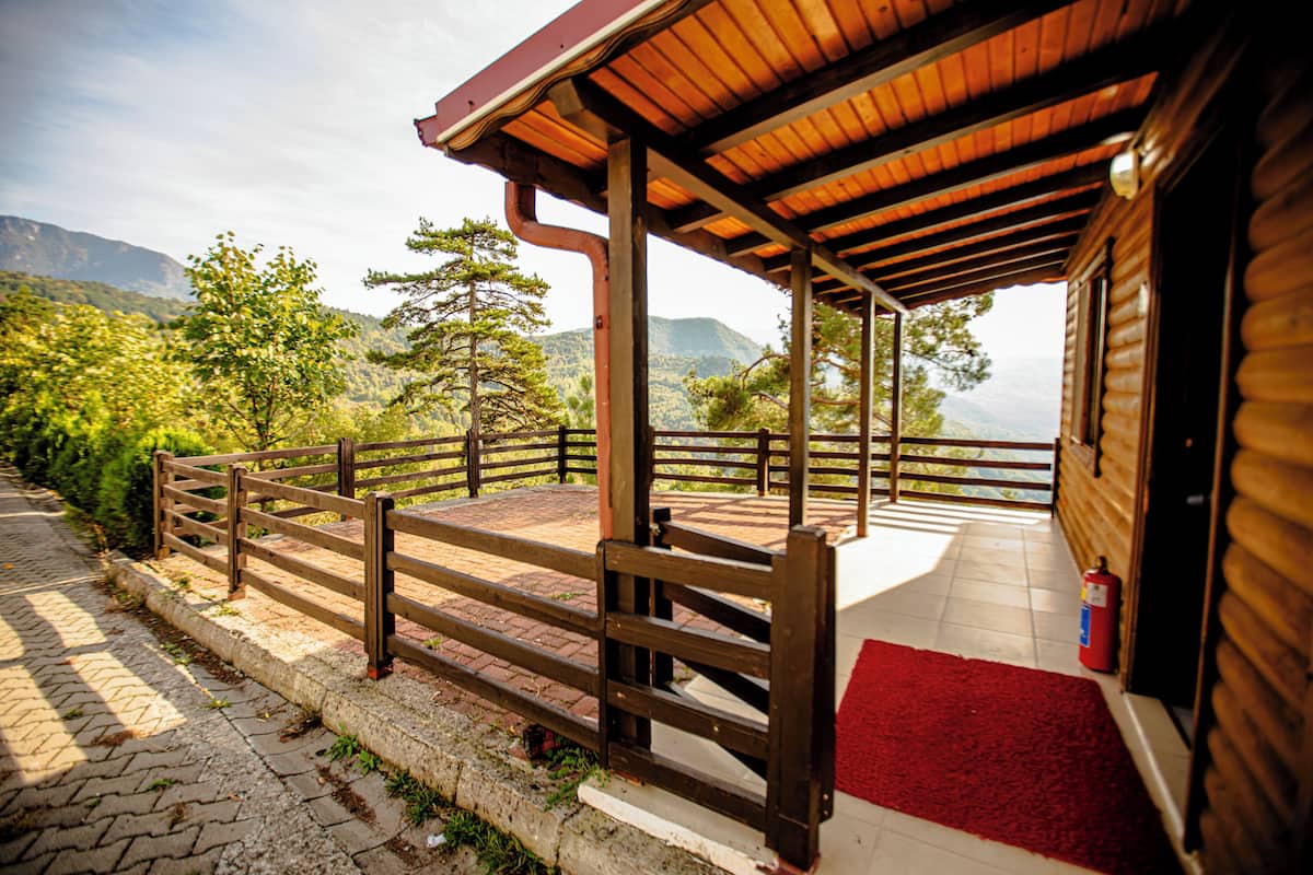 A wooden cabin with a covered porch, a red carpet, and a fire extinguisher.