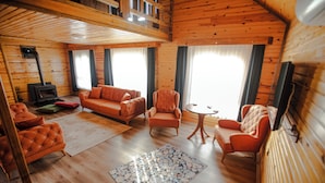 A cozy cabin interior with a fireplace, wooden walls, a sofa, armchairs, and a rug. - Ihlamur Teras Yenice (Yenice)