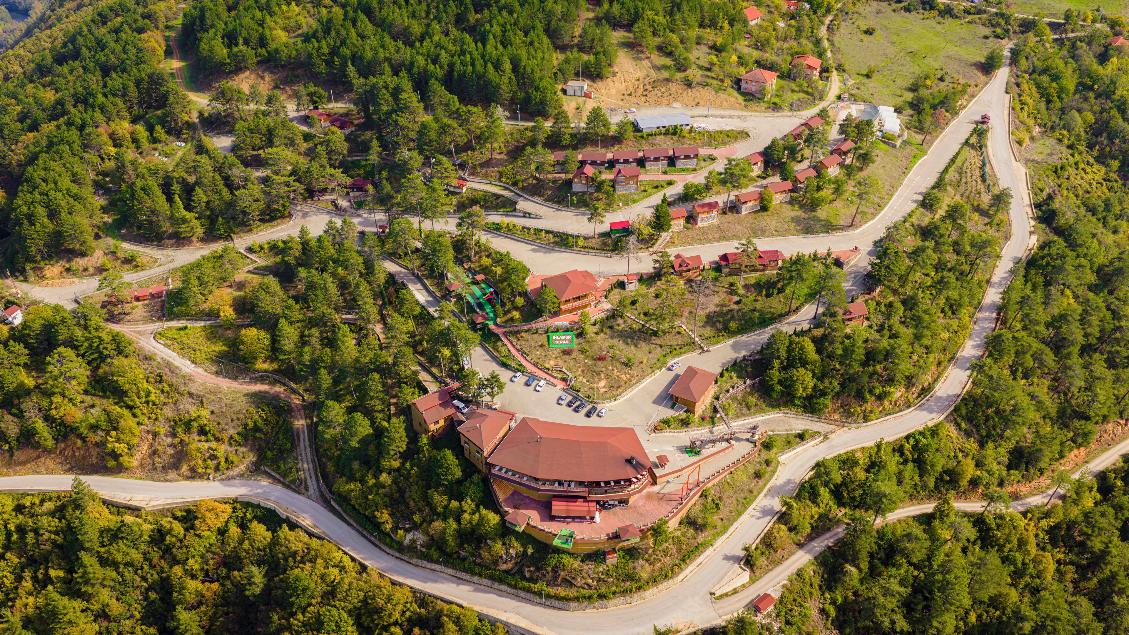 An aerial view of a resort with multiple buildings, winding roads, and dense forested areas.