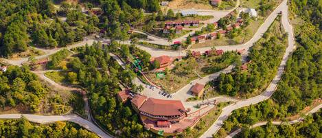 An aerial view of a resort with multiple buildings, winding roads, and dense forested areas.
