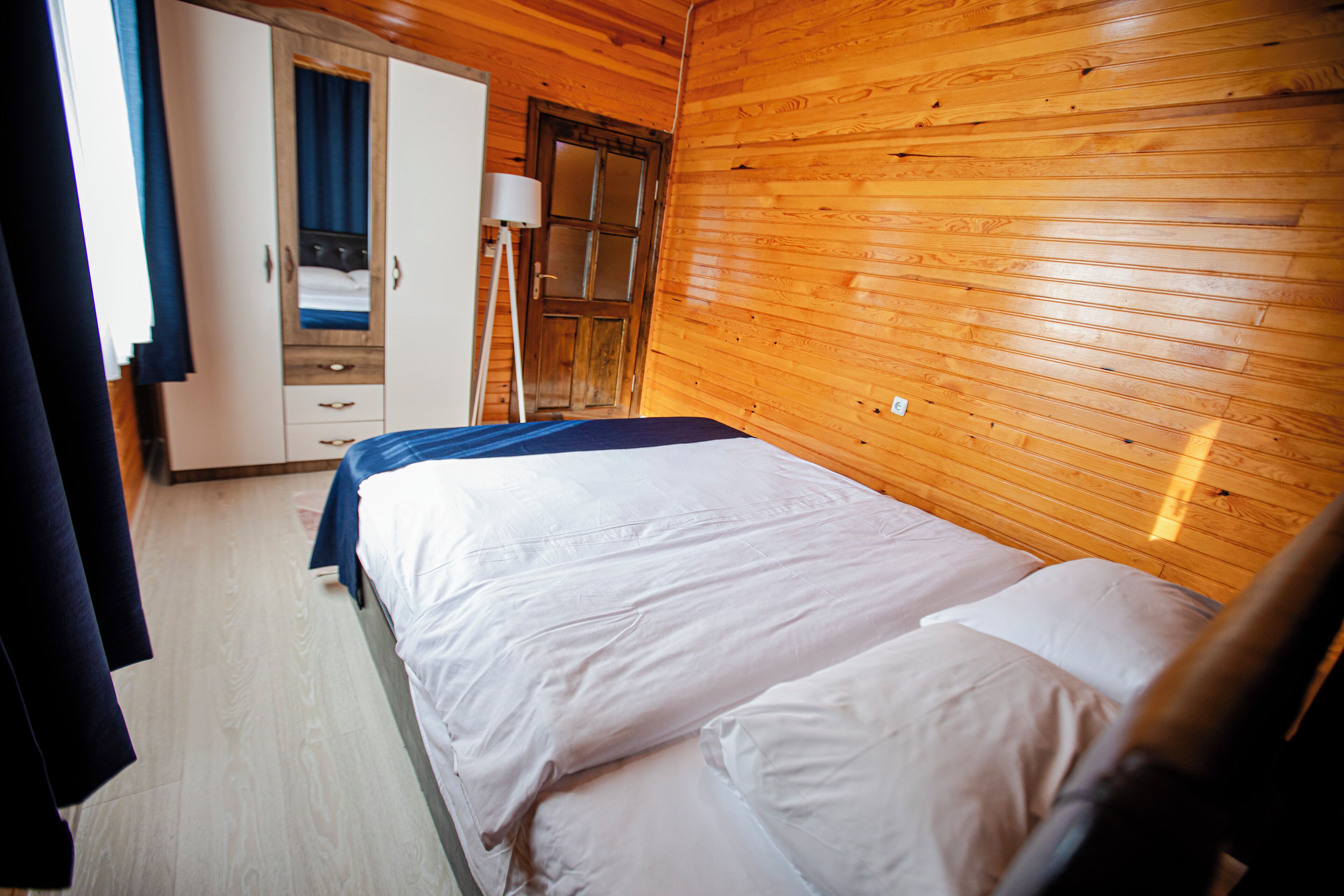 Una habitación con paneles de madera, una cama, un armario y una lámpara.