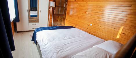 A wooden-paneled room with a bed, wardrobe, and a lamp.
