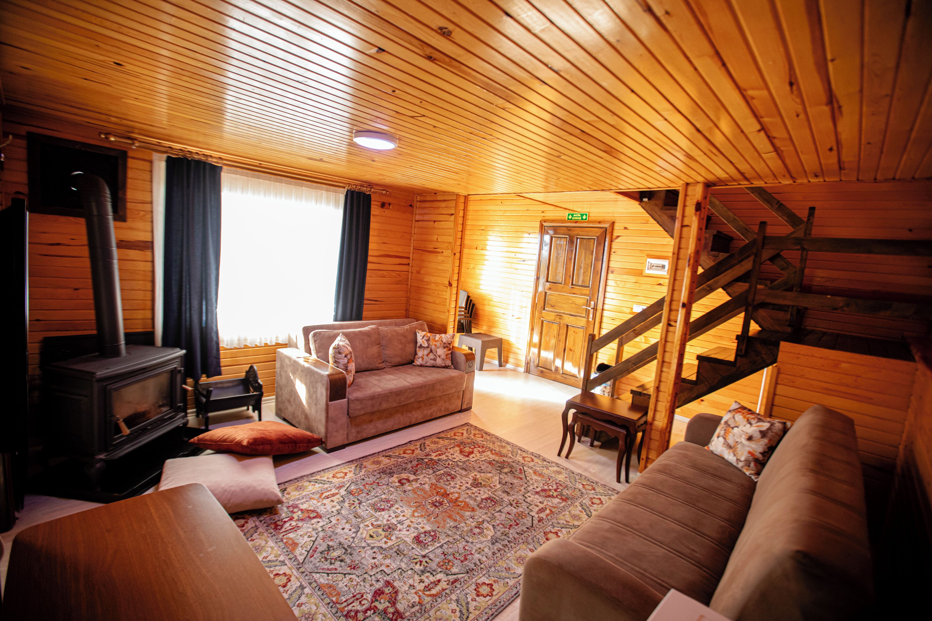 L’intérieur chaleureux d’un chalet en bois comprend un canapé, un tapis, une cheminée et un escalier.