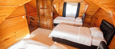 Eine dreieckige Holzhütte mit drei nebeneinanderliegenden Betten.