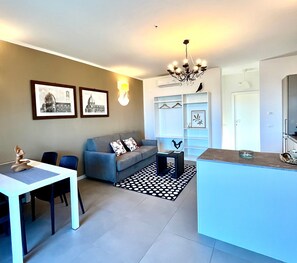 A modern living room with a sofa, a dining table, and a kitchen area with a counter.