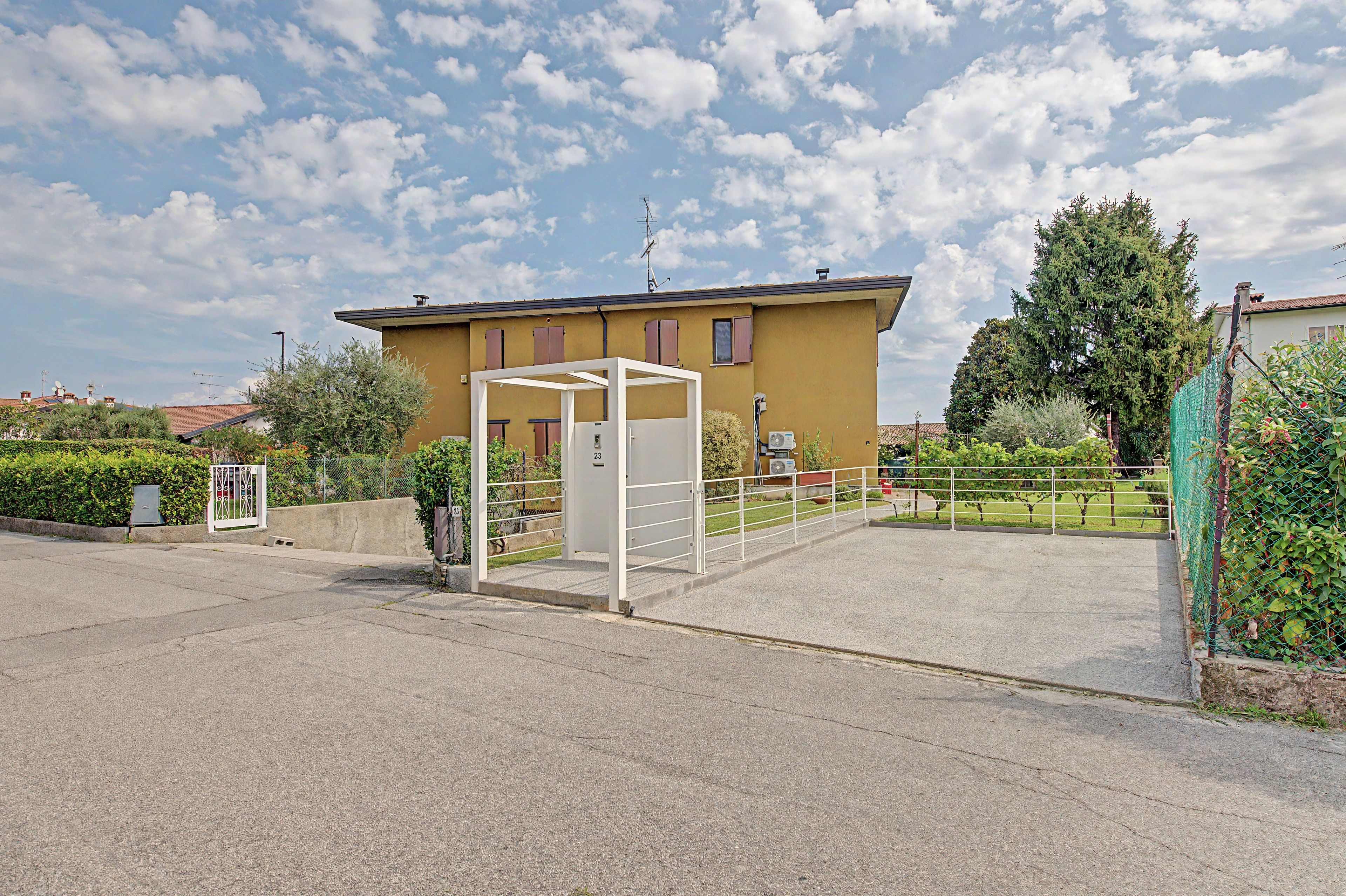 A building with a gated entrance, a clear sky, and a fenced garden area.