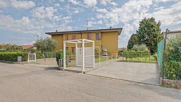 A building with a gated entrance, a clear sky, and a fenced garden area.