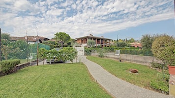 A residential area with a paved pathway, greenery, and houses.