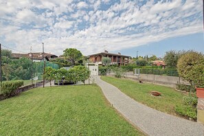 A residential area with a paved pathway, greenery, and houses. - Panoramic Apartment with Lake View, Wi-Fi, Air Conditioning & Private Parking (Padenghe Sul Garda)