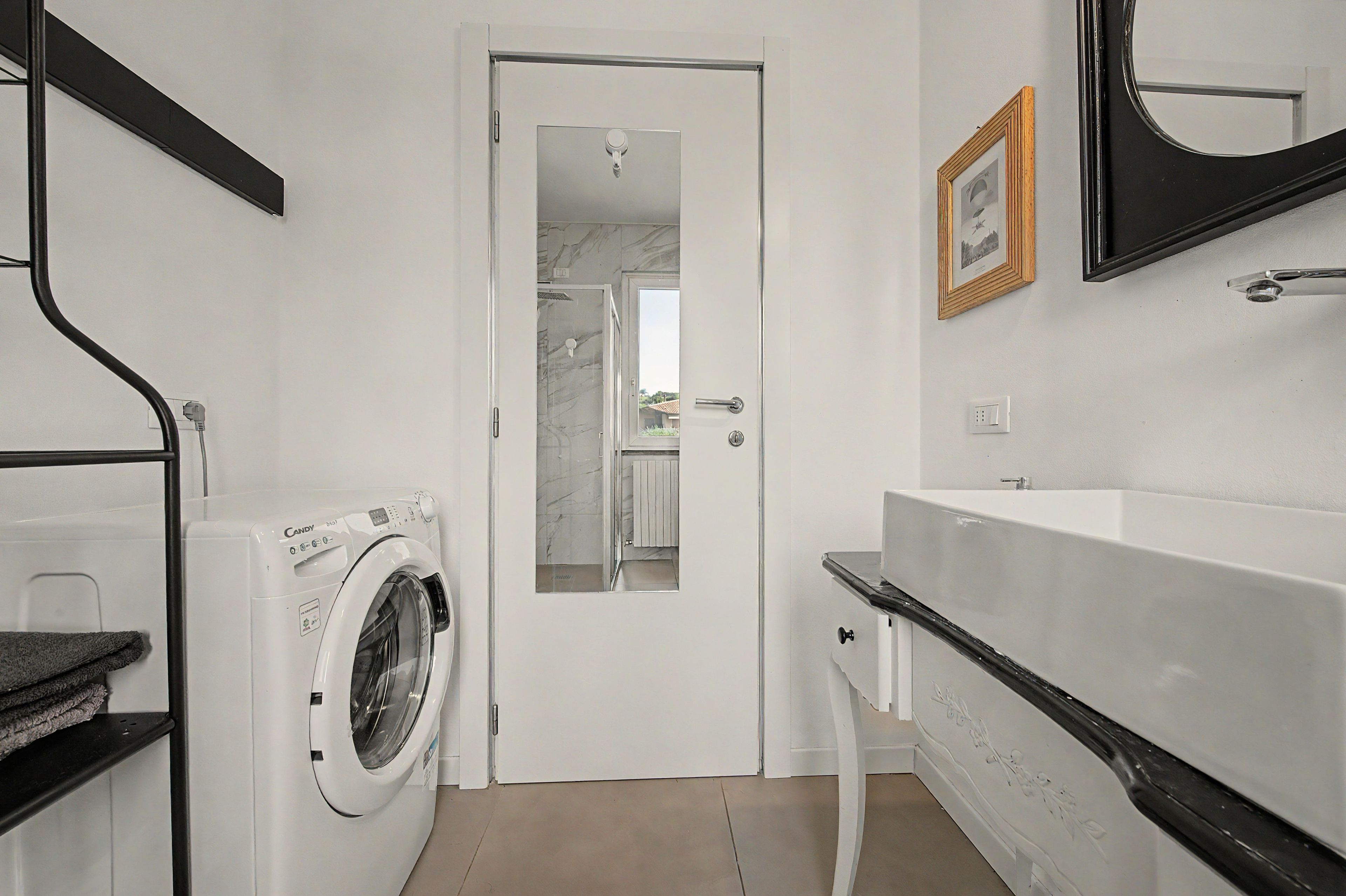 A modern bathroom with a washing machine, a bathtub, and a mirror.