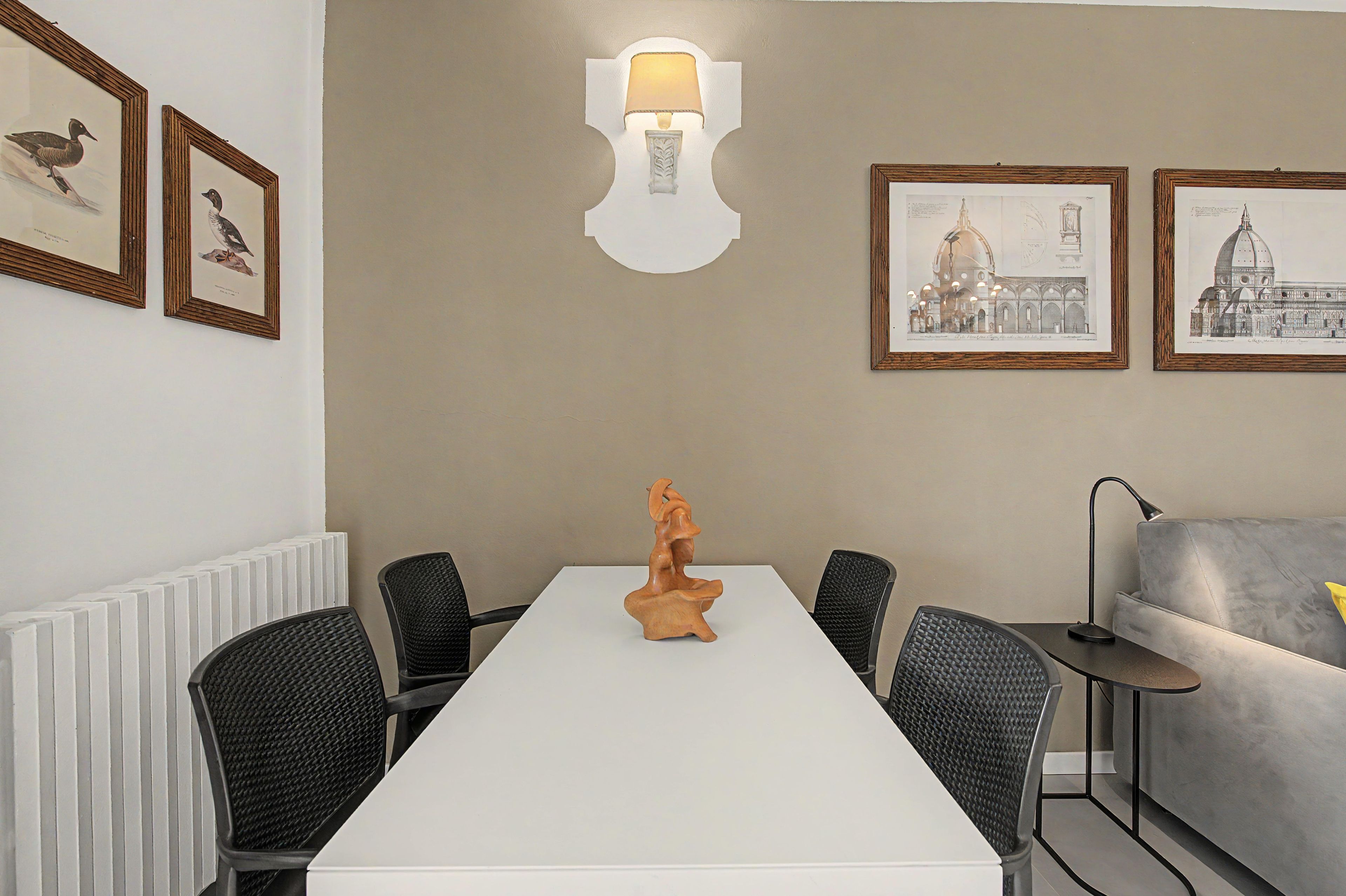 Une salle de conférence avec une table blanche, des chaises noires, une sculpture en bois comme élément central et des œuvres d’art encadrées accrochées aux murs.