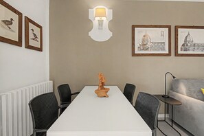 A conference room with a white table, black chairs, a wooden sculpture centerpiece, and framed artwork on the walls. - Panoramic Apartment with Lake View, Wi-Fi, Air Conditioning & Private Parking (Padenghe Sul Garda)