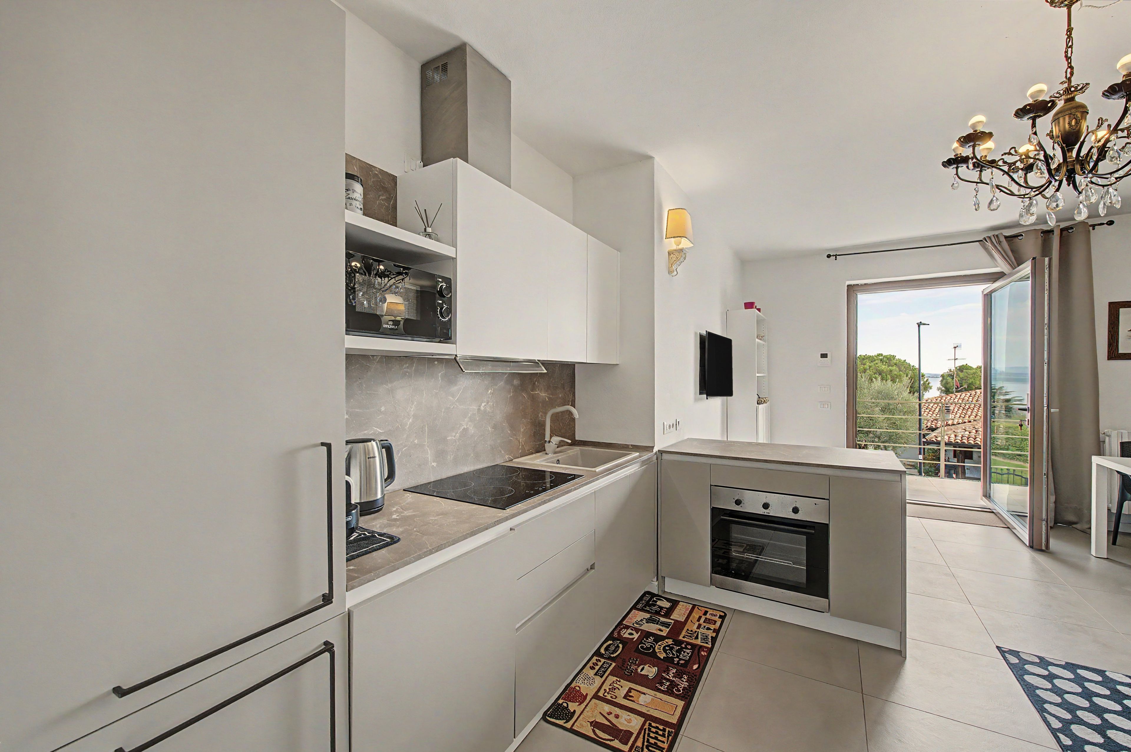 A modern kitchen with white cabinetry, a built-in oven, and a coffee machine.