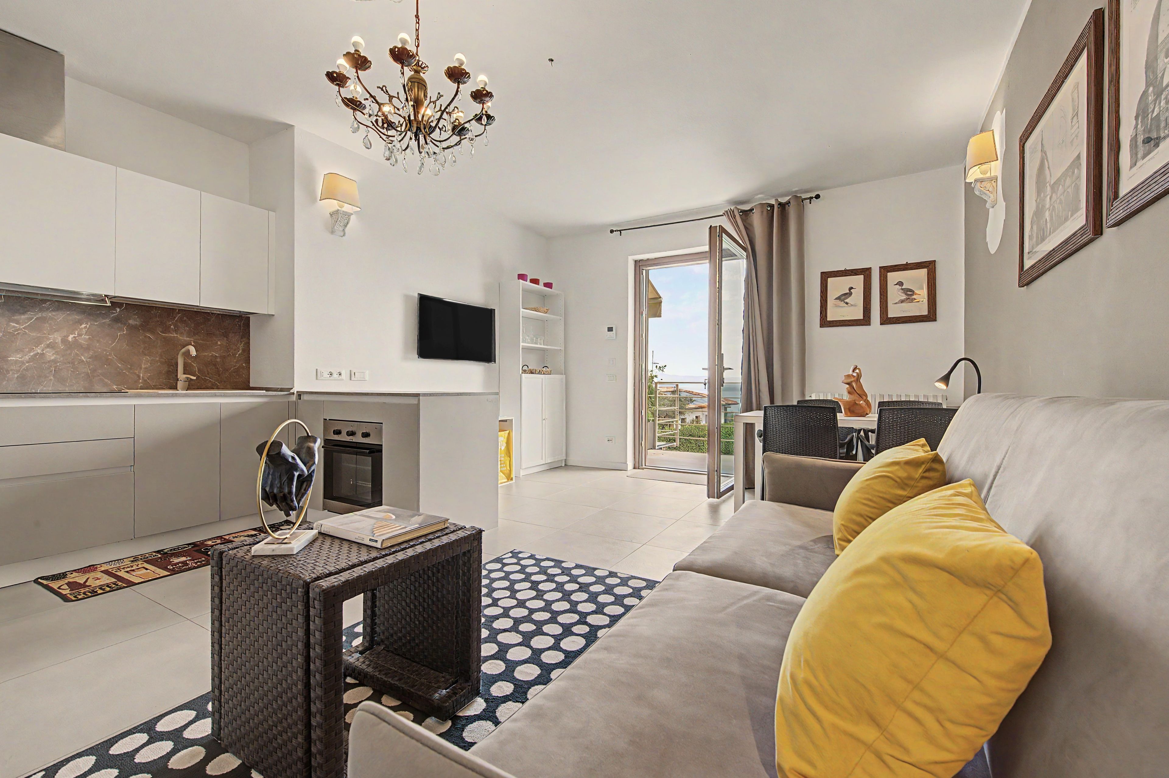 Ein modernes Wohnzimmer mit Sofa, Essbereich, Küche und einem Balkon mit Blick.