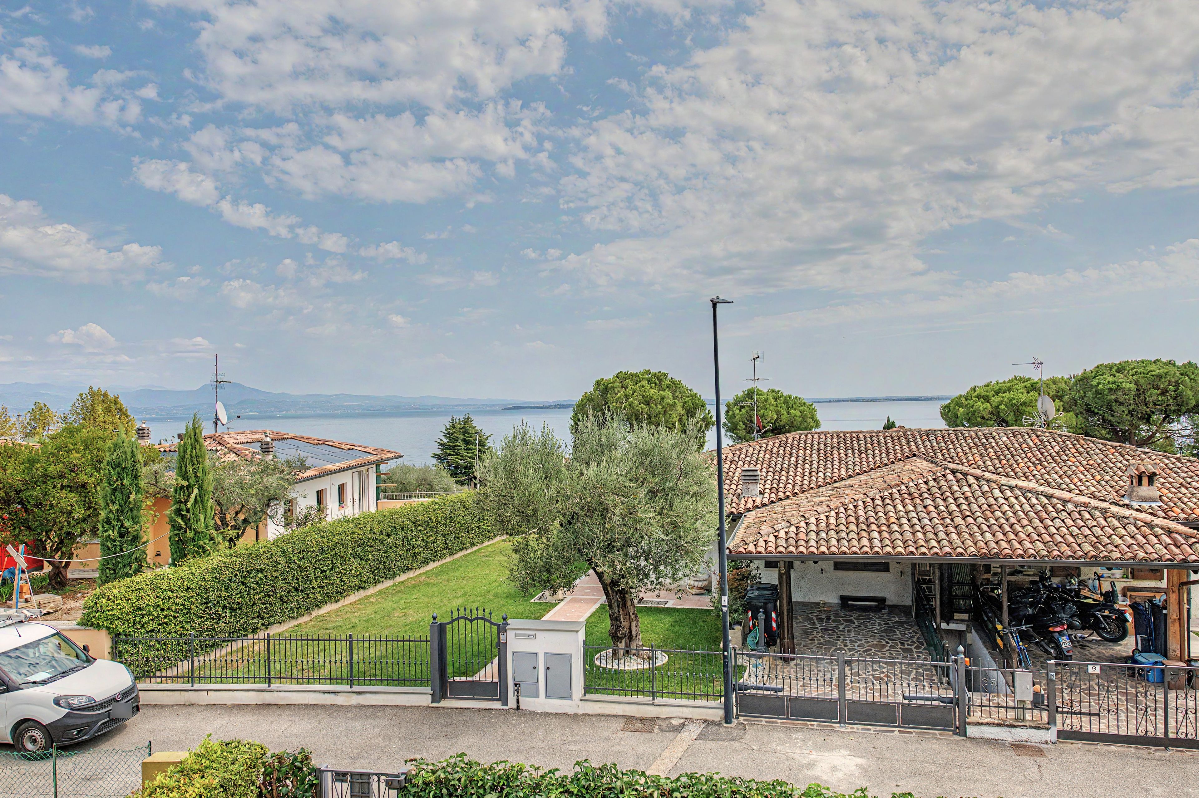 A coastal property with a tiled roof, a fenced garden, and a view of the sea.