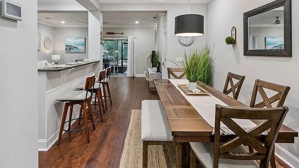 Een moderne eetruimte met een lange houten tafel, stoelen en een hanglamp.