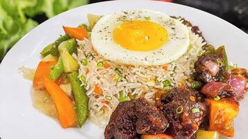 Un plato de arroz frito con verduras y un huevo frito encima.