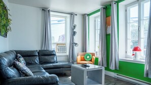 A modern living room with a black leather sofa, a grey coffee table, and a green accent wall.