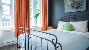 A bedroom with a bed, a nightstand, a lamp, and a window with curtains.