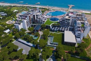 An aerial view of a hotel complex with multiple buildings, a swimming pool, and a beach. - Selectum Luxury Resort Belek (Serik)