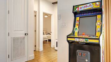 Une pièce avec un lit, une porte et une borne d’arcade aux couleurs vives.
